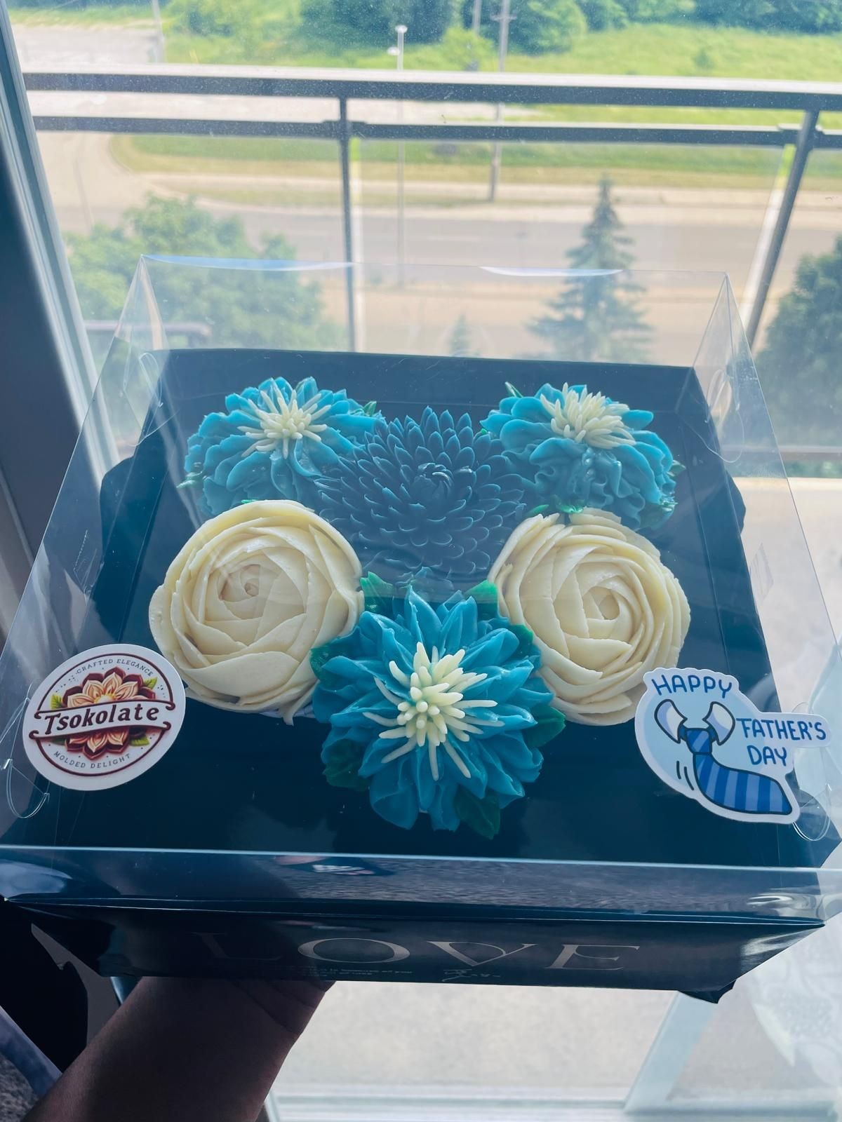 Box of blue and white floral cupcakes with 'Happy Father's Day' decal.