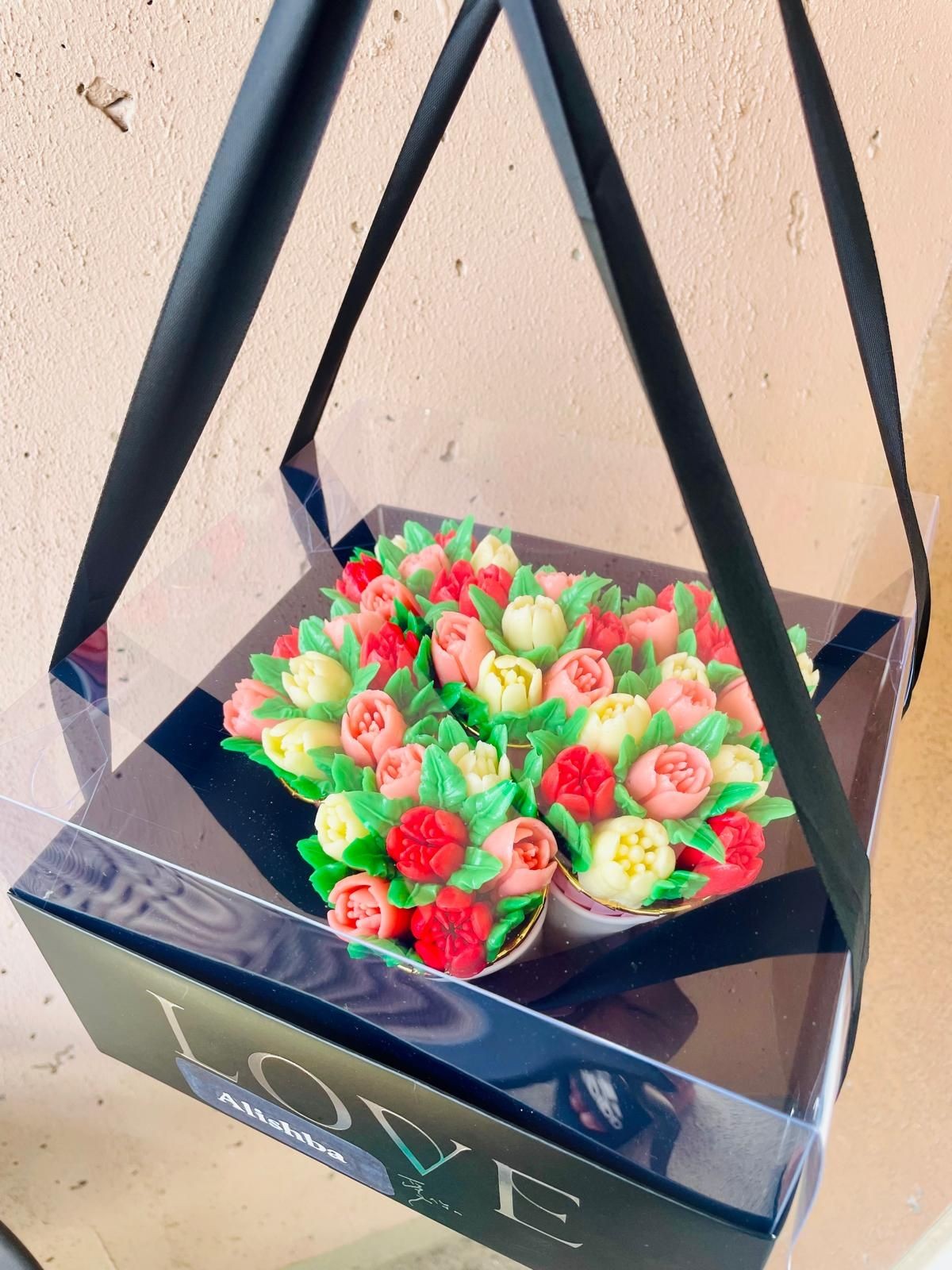 Box of colorful flower-like cupcakes with 'LOVE' on the front.